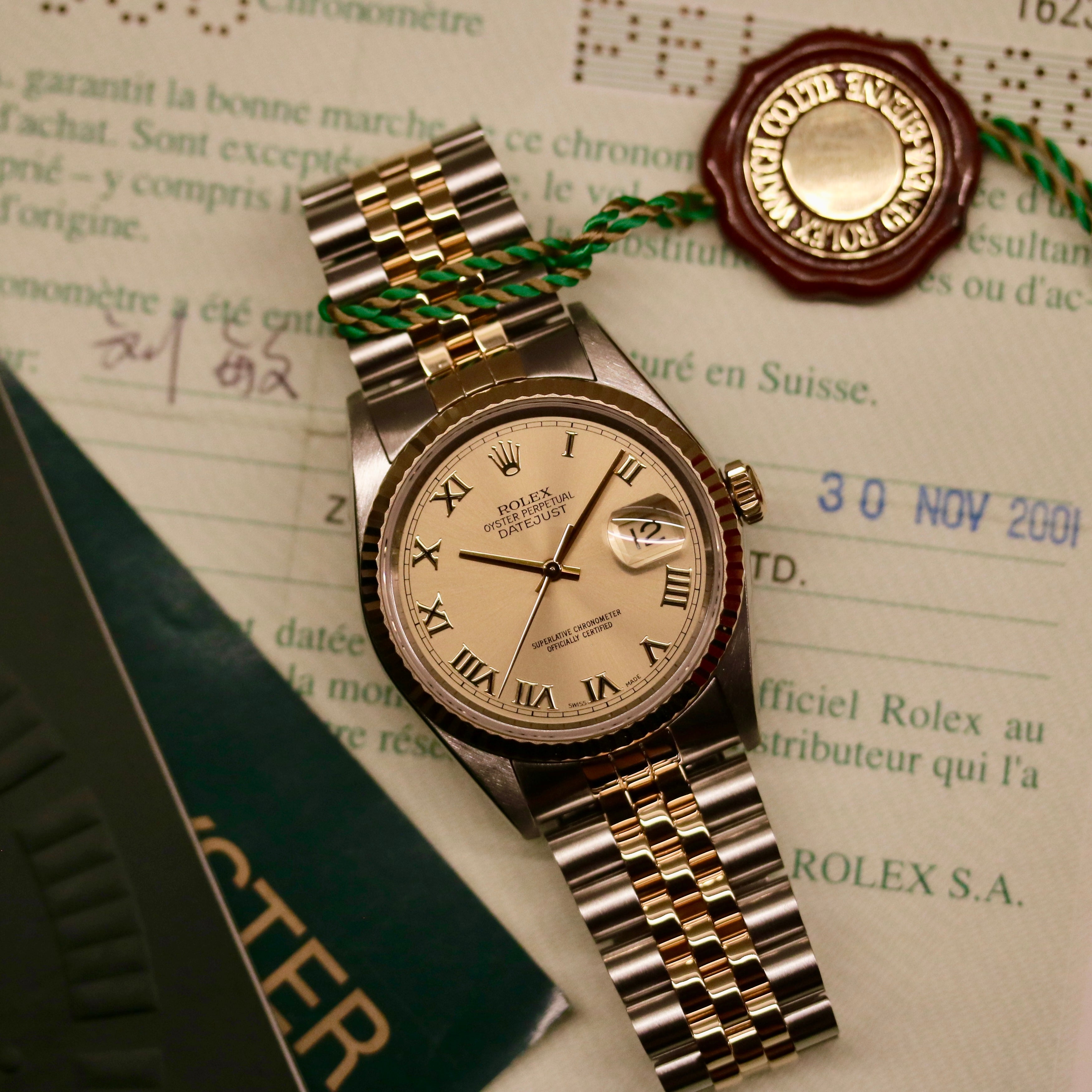 Rolex Datejust 36 ref. 16233 from 2003 in two-tone steel and yellow gold with a champagne Roman numeral dial, 36mm case, Jubilee bracelet, sapphire crystal, and automatic movement. Detailed product photos showing the fluted yellow-gold bezel, Roman hour markers, bracelet links, clasp, and overall condition. Includes original Hong Kong 2003 certificate, box, and tag, offered by Klocksalongen with a 12-month functional warranty.