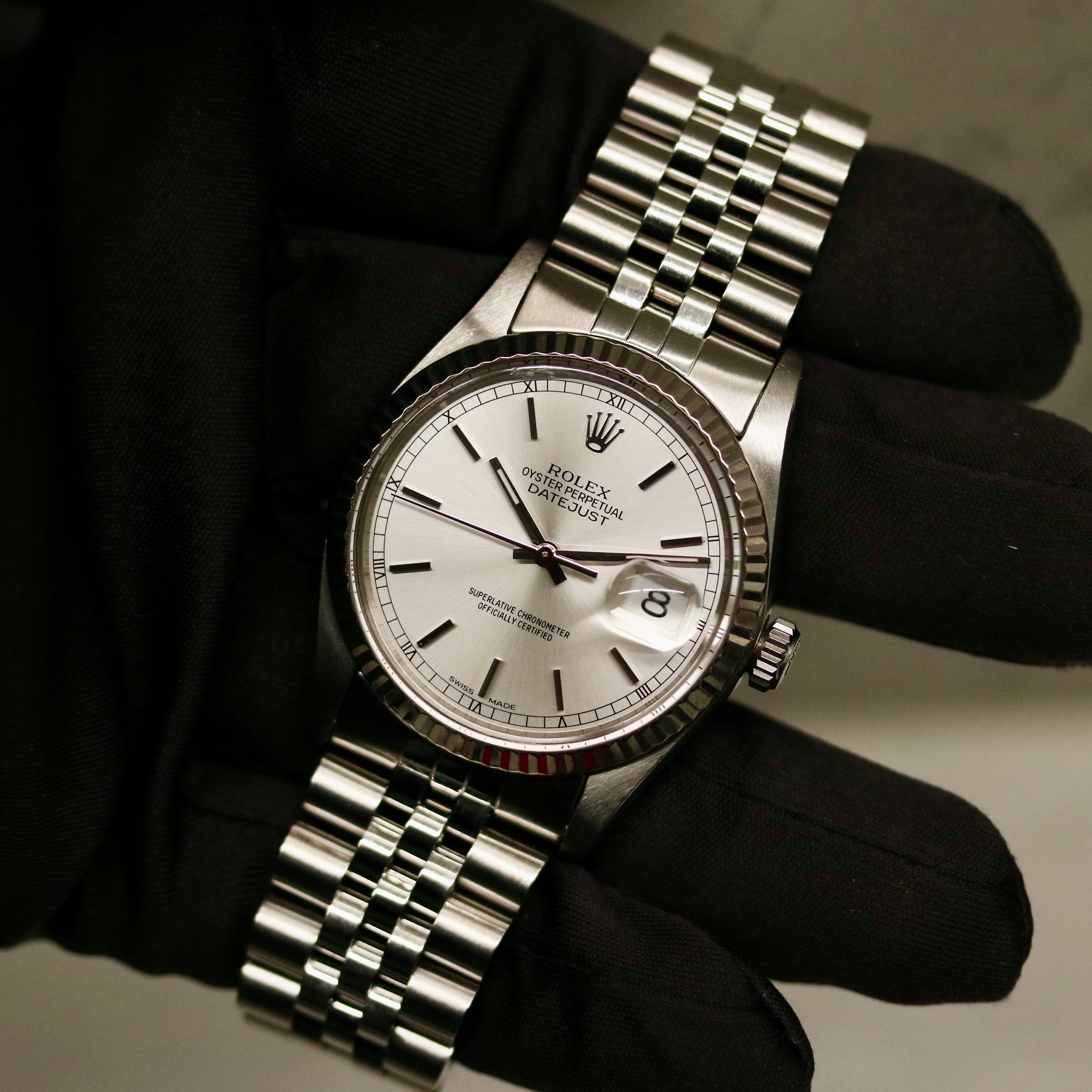 Rolex Datejust 36 ref. 16014 from 1984 with a white-gold fluted bezel and stainless-steel case and bracelet, featuring a silver dial, sapphire crystal, automatic movement, and very good condition; detailed product photos showing the dial, bezel, case profile, bracelet, and overall finishing, offered by Klocksalongen with authenticity certificate and 12-month functional warranty.