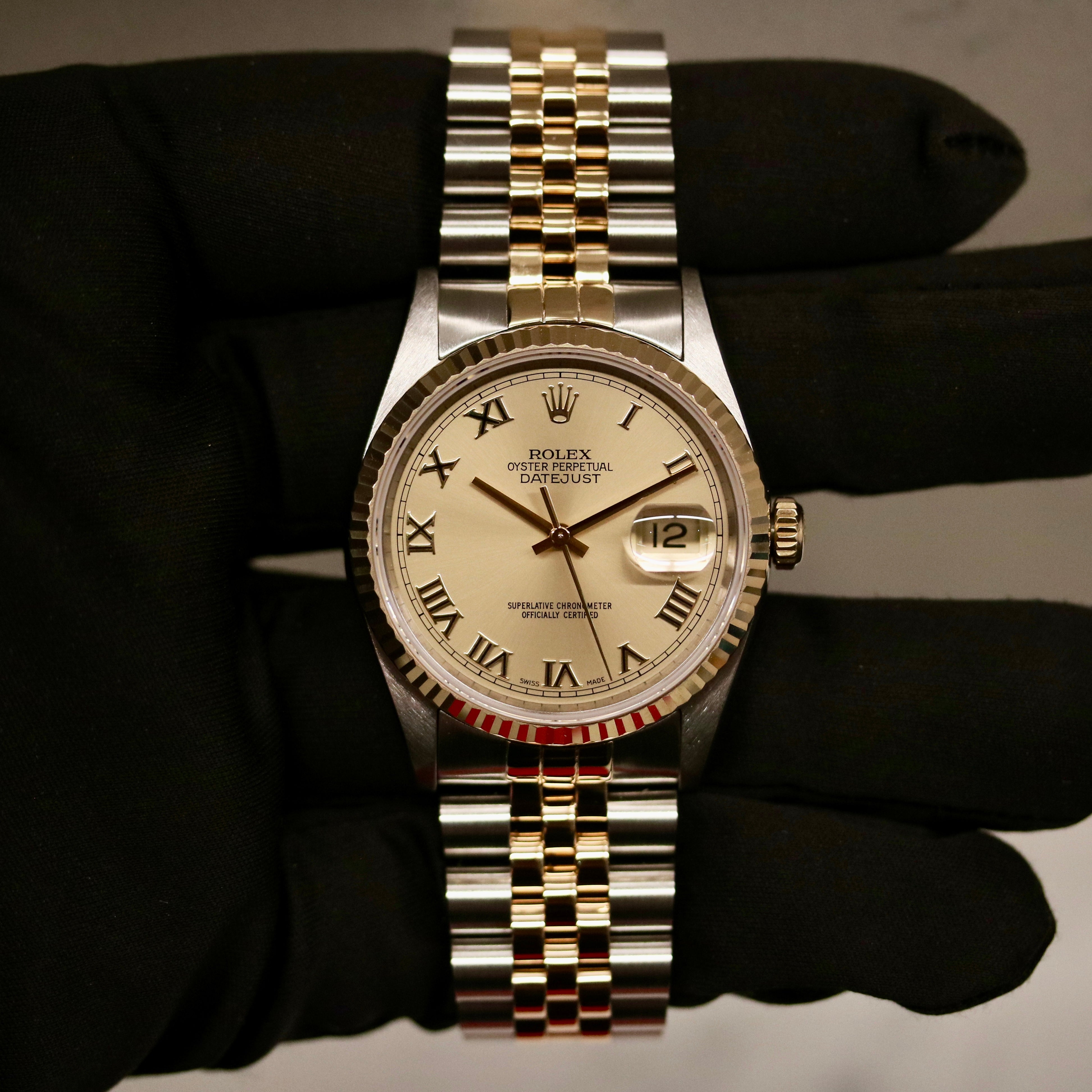 Rolex Datejust 36 ref. 16233 from 2003 in two-tone steel and yellow gold with a champagne Roman numeral dial, 36mm case, Jubilee bracelet, sapphire crystal, and automatic movement. Detailed product photos showing the fluted yellow-gold bezel, Roman hour markers, bracelet links, clasp, and overall condition. Includes original Hong Kong 2003 certificate, box, and tag, offered by Klocksalongen with a 12-month functional warranty.