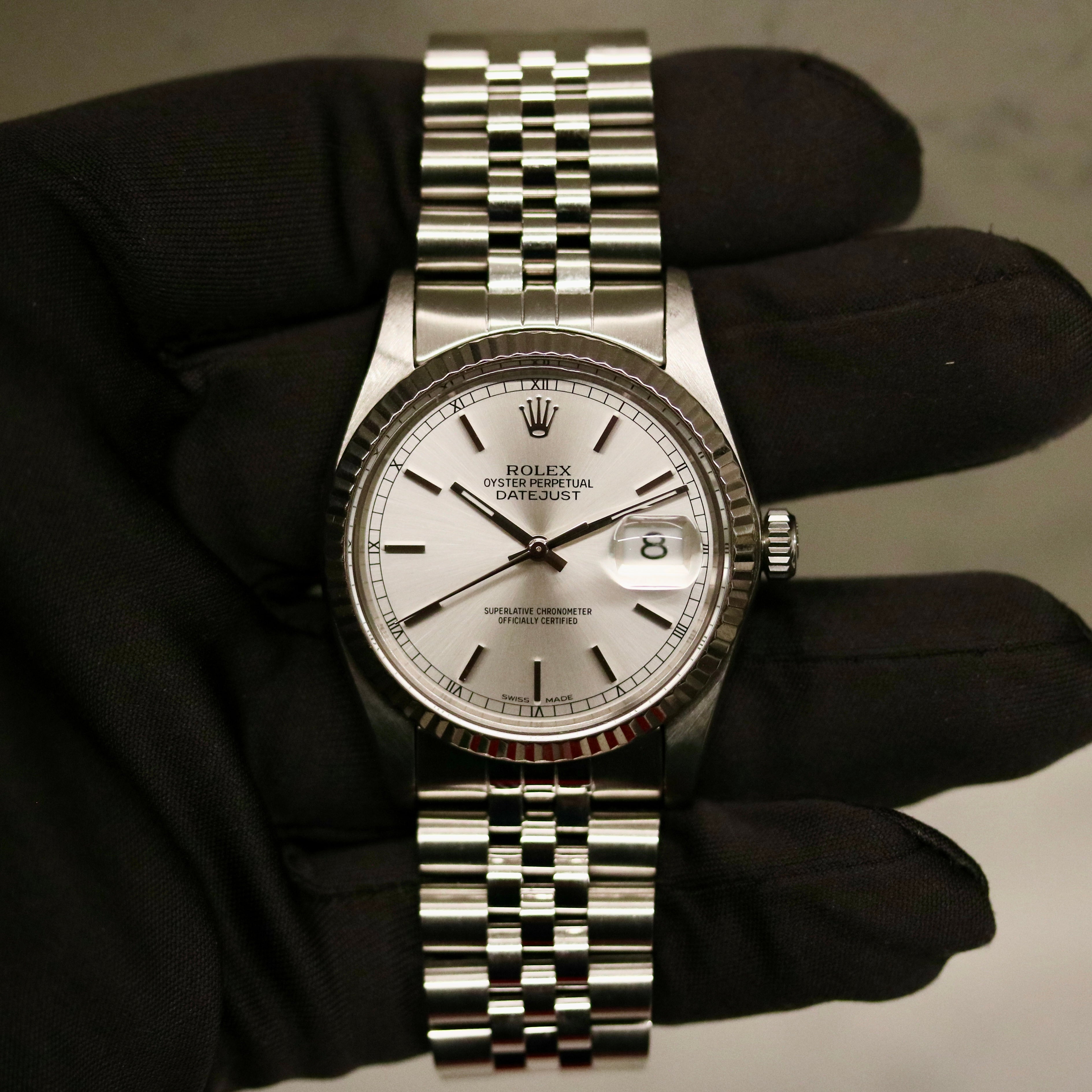Rolex Datejust 36 ref. 16014 from 1984 with a white-gold fluted bezel and stainless-steel case and bracelet, featuring a silver dial, sapphire crystal, automatic movement, and very good condition; detailed product photos showing the dial, bezel, case profile, bracelet, and overall finishing, offered by Klocksalongen with authenticity certificate and 12-month functional warranty.