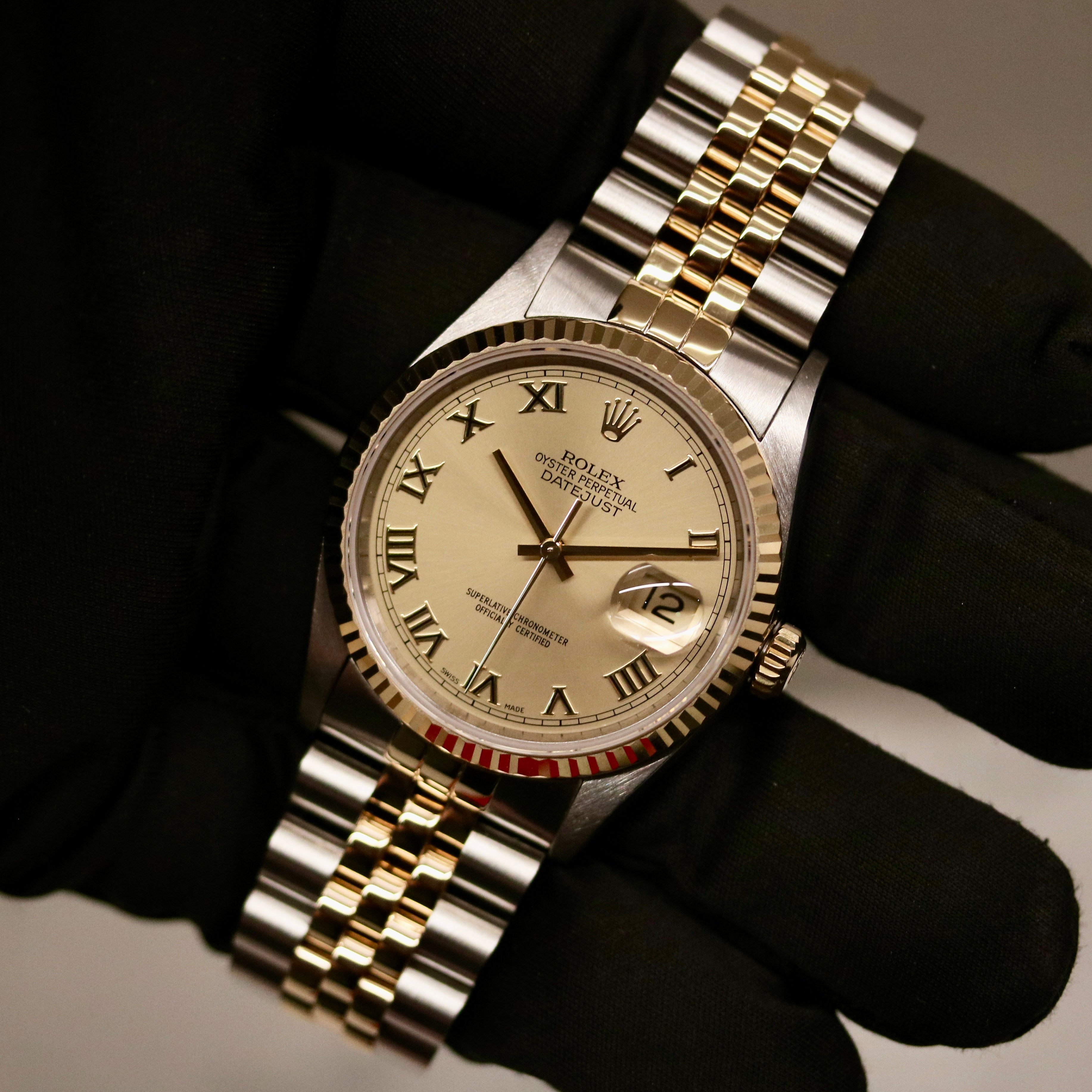 Rolex Datejust 36 ref. 16233 from 2003 in two-tone steel and yellow gold with a champagne Roman numeral dial, 36mm case, Jubilee bracelet, sapphire crystal, and automatic movement. Detailed product photos showing the fluted yellow-gold bezel, Roman hour markers, bracelet links, clasp, and overall condition. Includes original Hong Kong 2003 certificate, box, and tag, offered by Klocksalongen with a 12-month functional warranty.