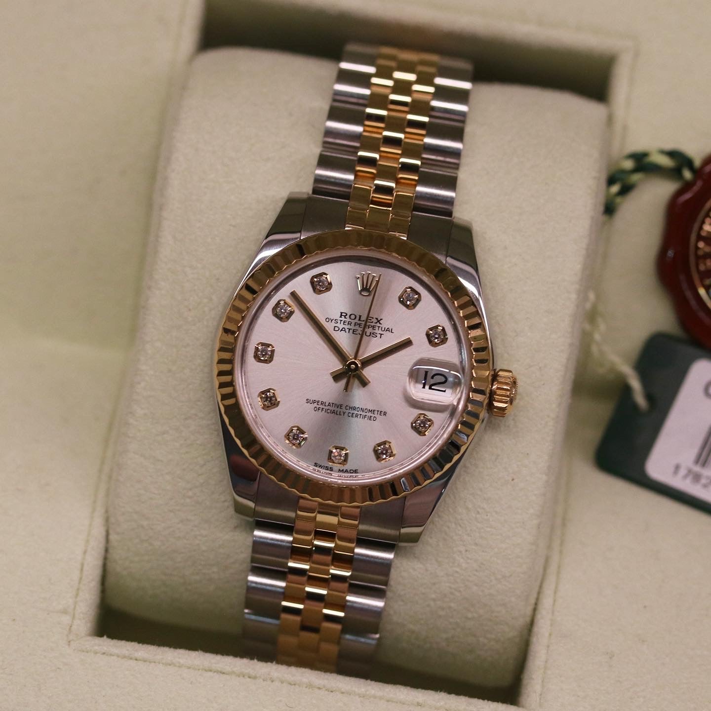 Rolex Datejust 31 ref. 178273 from 2012 in two-tone stainless steel and yellow gold with a factory silver diamond dial, 31mm case, Jubilee bracelet, sapphire crystal, and automatic movement. Presented in very good condition with original 2012 Netherlands certificate, box, tags, certificate holder, and booklets. Detailed product photos show the diamond markers, fluted bezel, case, bracelet, and clasp, offered by Klocksalongen with a 12-month functional warranty.