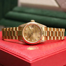 Rolex Datejust 31 ref. 68238 from 2000 in solid yellow gold with factory diamond-set bezel and a factory champagne big diamond dial, 31mm case, President bracelet, sapphire crystal, and automatic movement. Excellent condition, freshly serviced, and complete with original 2000 Spain certificate, box, booklets, and tag. Detailed product photos showing the diamond bezel, large diamond markers, gold case, bracelet, clasp, and finishing, offered by Klocksalongen with a 12-month service warranty.