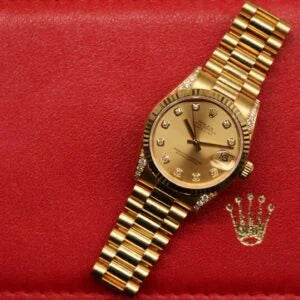 Rolex Datejust 31 ref. 68238 from 2000 in solid yellow gold with factory diamond-set bezel and a factory champagne big diamond dial, 31mm case, President bracelet, sapphire crystal, and automatic movement. Excellent condition, freshly serviced, and complete with original 2000 Spain certificate, box, booklets, and tag. Detailed product photos showing the diamond bezel, large diamond markers, gold case, bracelet, clasp, and finishing, offered by Klocksalongen with a 12-month service warranty.