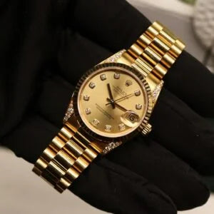 Rolex Datejust 31 ref. 68238 from 2000 in solid yellow gold with factory diamond-set bezel and a factory champagne big diamond dial, 31mm case, President bracelet, sapphire crystal, and automatic movement. Excellent condition, freshly serviced, and complete with original 2000 Spain certificate, box, booklets, and tag. Detailed product photos showing the diamond bezel, large diamond markers, gold case, bracelet, clasp, and finishing, offered by Klocksalongen with a 12-month service warranty.