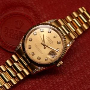 Rolex Datejust 31 ref. 68238 from 2000 in solid yellow gold with factory diamond-set bezel and a factory champagne big diamond dial, 31mm case, President bracelet, sapphire crystal, and automatic movement. Excellent condition, freshly serviced, and complete with original 2000 Spain certificate, box, booklets, and tag. Detailed product photos showing the diamond bezel, large diamond markers, gold case, bracelet, clasp, and finishing, offered by Klocksalongen with a 12-month service warranty.