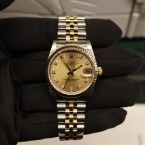 Rolex Datejust 31 ref. 68273 from 1989 in two-tone stainless steel and yellow gold with a factory champagne diamond dial, 31mm case, Jubilee bracelet, sapphire crystal, and automatic movement. Freshly serviced and polished, in very good condition. Complete full set including original 1989 USA certificate, box, booklets, and tag. Detailed product photos showing the diamond-set dial, fluted bezel, case, bracelet, and clasp, offered by Klocksalongen with a 12-month service warranty.
