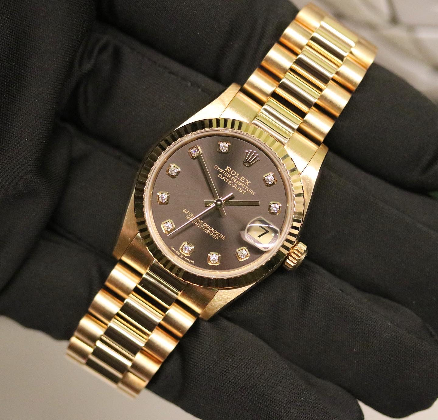 Rolex Datejust 31 ref. 68278 from 1989 in solid yellow gold with a rare factory chocolate/dark grey diamond dial (2020 version), 31mm case, President bracelet, sapphire crystal, and automatic movement. Presented in superb condition and complete with original Italy 1989 certificate, box, booklets, and tag. Detailed photos showing the upgraded dial, diamond markers, gold bezel, case, bracelet, and clasp, offered by Klocksalongen with a 12-month functional warranty.