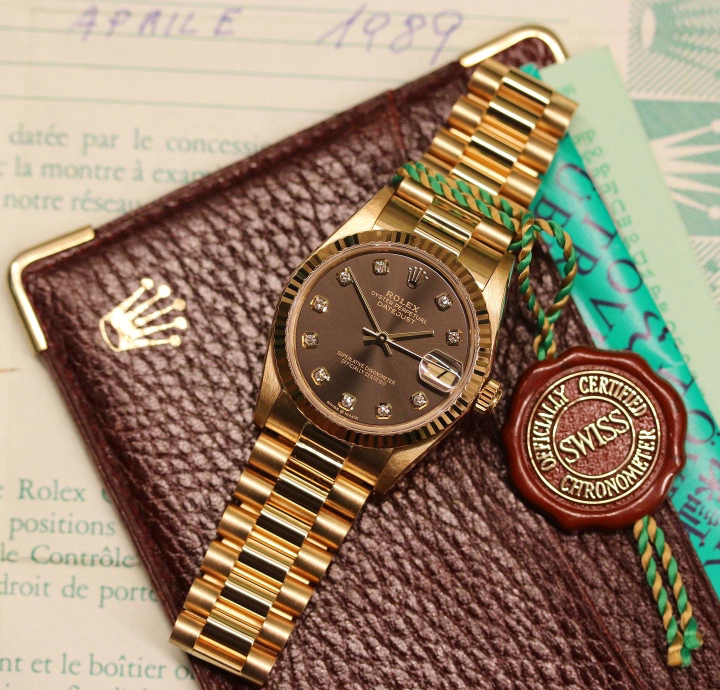 Rolex Datejust 31 ref. 68278 from 1989 in solid yellow gold with a rare factory chocolate/dark grey diamond dial (2020 version), 31mm case, President bracelet, sapphire crystal, and automatic movement. Presented in superb condition and complete with original Italy 1989 certificate, box, booklets, and tag. Detailed photos showing the upgraded dial, diamond markers, gold bezel, case, bracelet, and clasp, offered by Klocksalongen with a 12-month functional warranty.