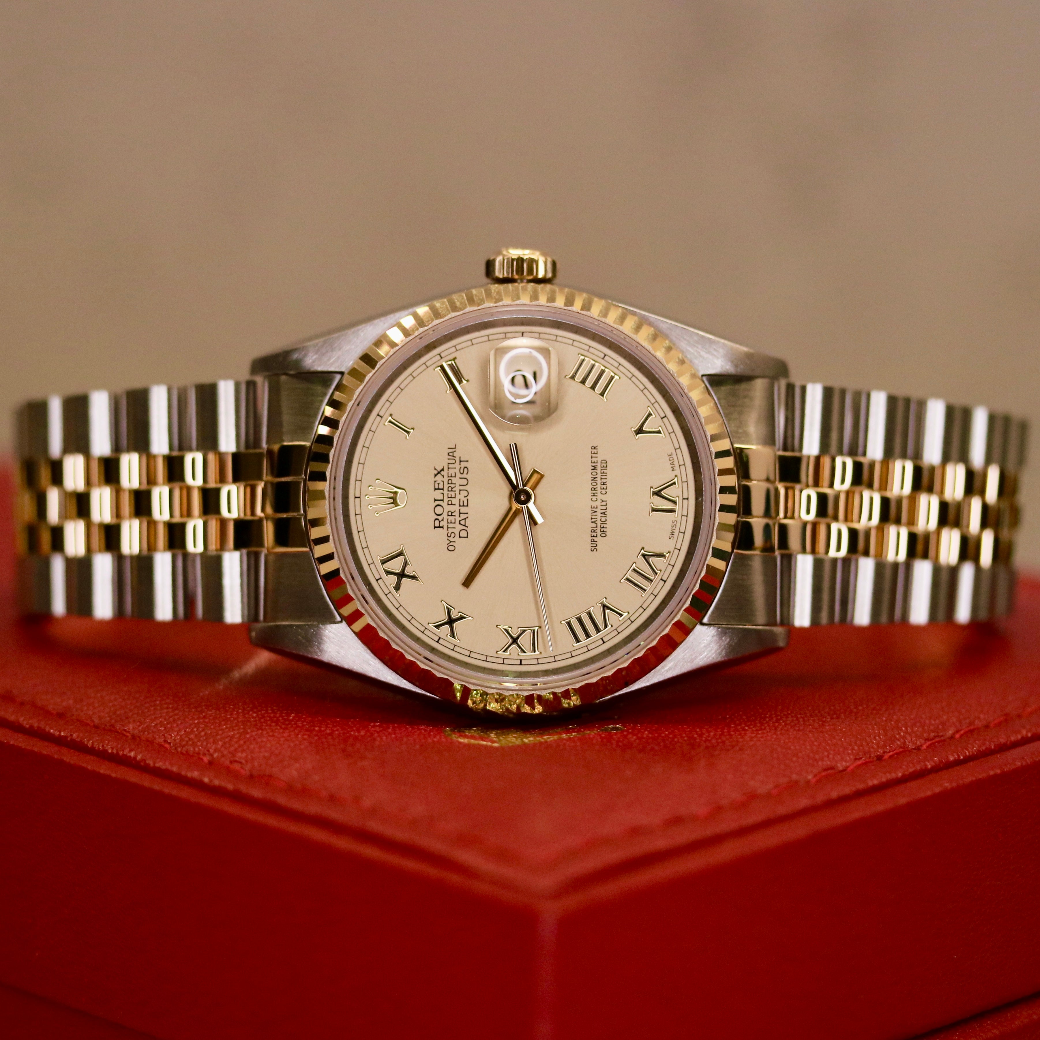 Rolex Datejust 36 ref. 16233 from 2003 in two-tone steel and yellow gold with a champagne Roman numeral dial, 36mm case, Jubilee bracelet, sapphire crystal, and automatic movement. Detailed product photos showing the fluted yellow-gold bezel, Roman hour markers, bracelet links, clasp, and overall condition. Includes original Hong Kong 2003 certificate, box, and tag, offered by Klocksalongen with a 12-month functional warranty.